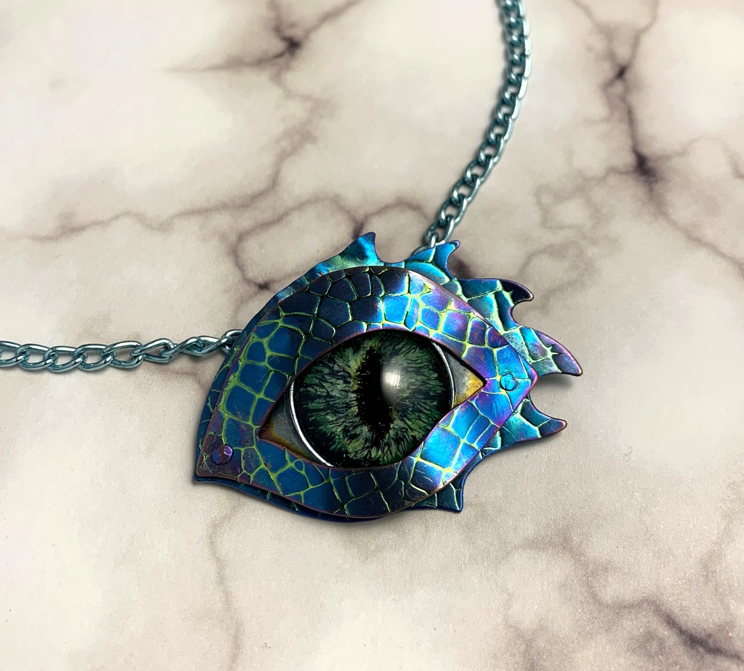 Blue green embossed and anodized niobium dragon eye painted with nail polishes